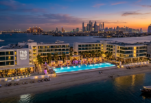 The stylish infinity pool and beachfront cabanas of Th8 Palm Dubai Beach Resort Vignette Collection under a clear sky.