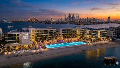 The stylish infinity pool and beachfront cabanas of Th8 Palm Dubai Beach Resort Vignette Collection under a clear sky.